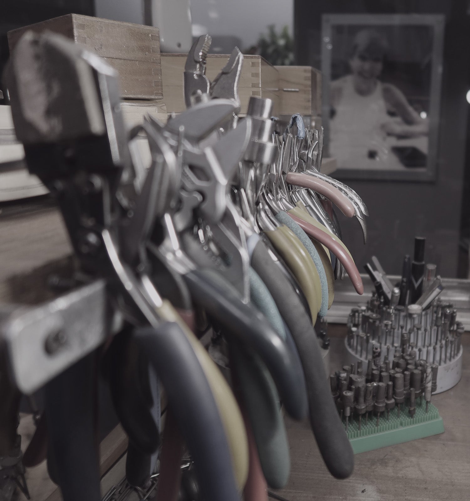 pliers and other tools on jewelers bench with photo of founder Linda McGill in the background