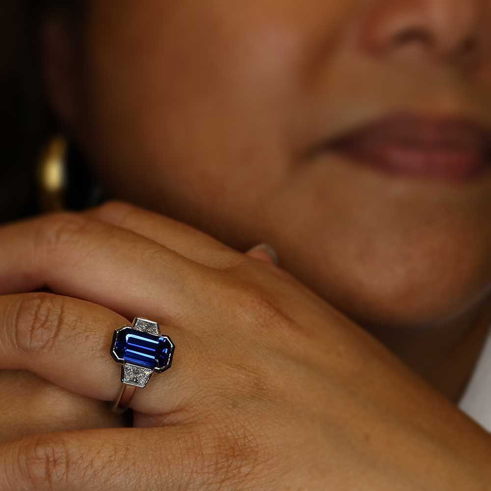 model wearing emerald cut sapphire and trapezoid diamond ring
