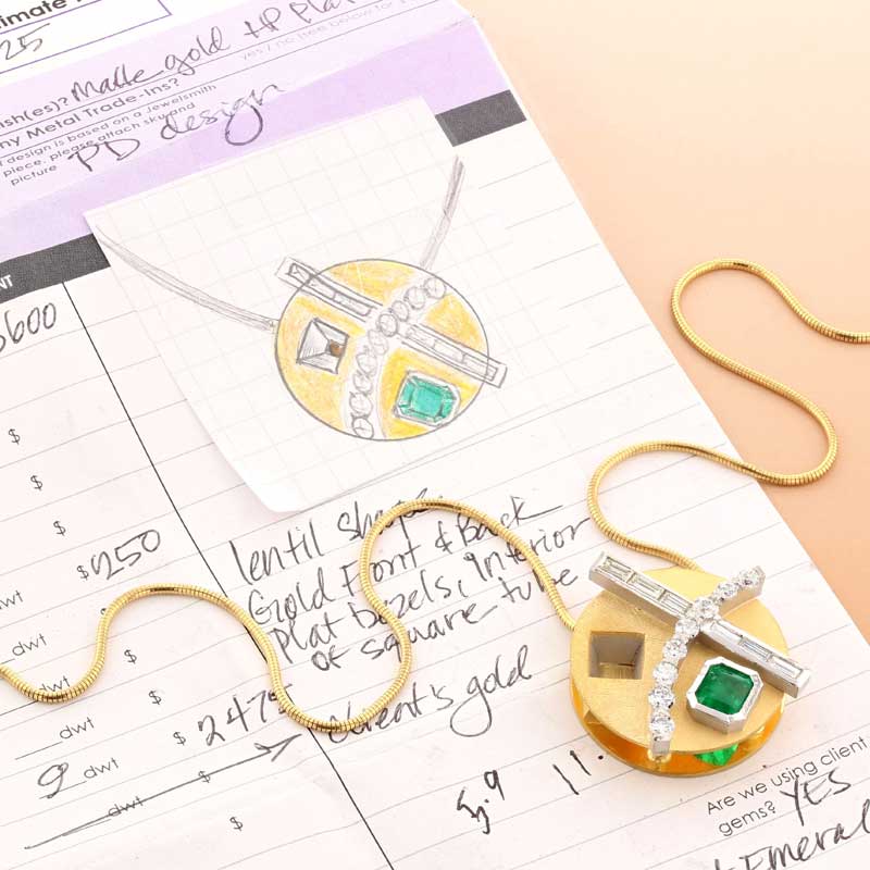 Finished custom emerald and diamond pendant laying on the hand-drawn sketch used to design it — Jewelsmith Durham NC